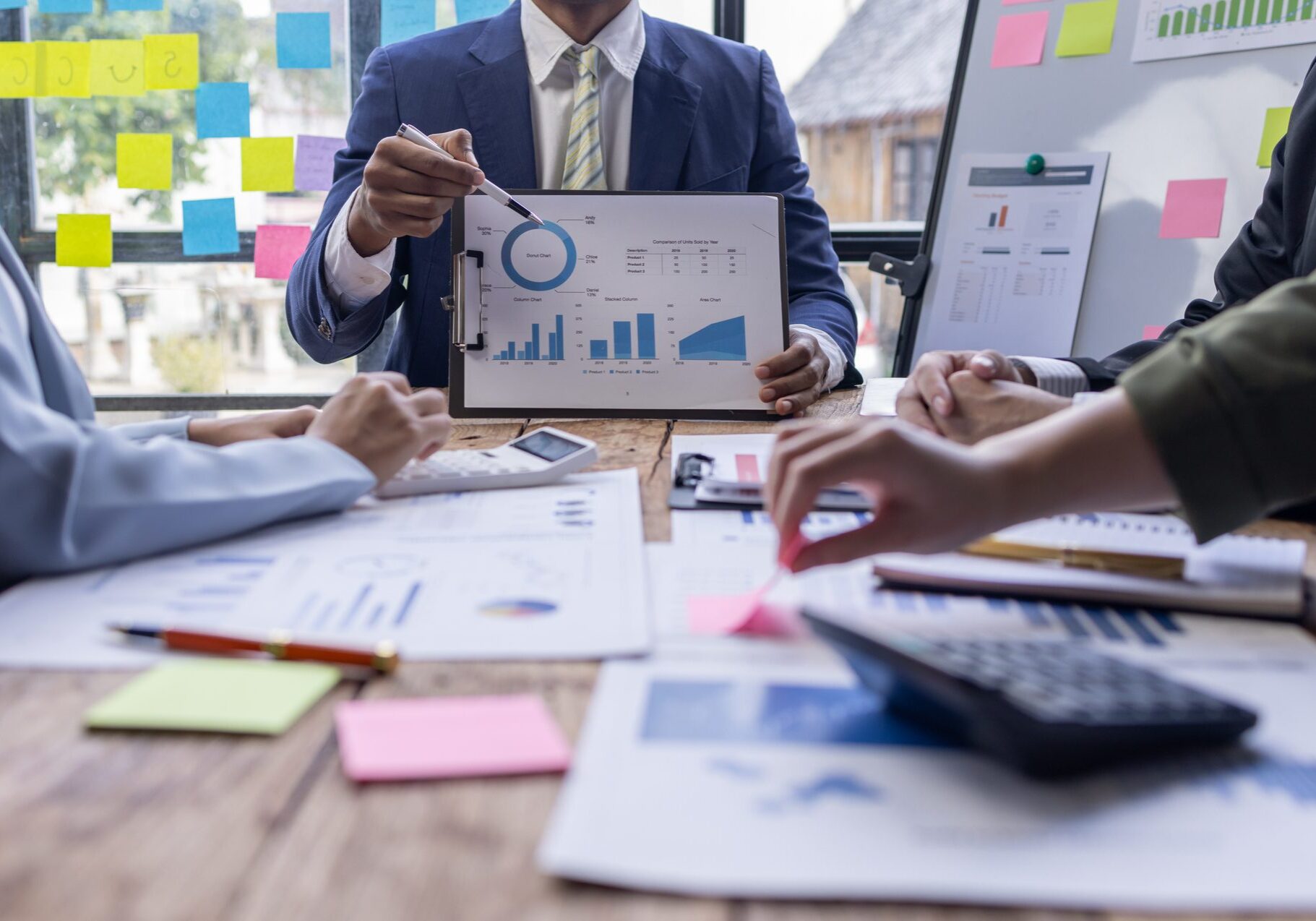 Group of confident business people point to graphs and charts to analyze market data, balance sheet, account, net profit to plan new sales strategies to increase production capacity.